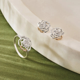 Silver ring and earrings with rose design on a green and beige fabric background