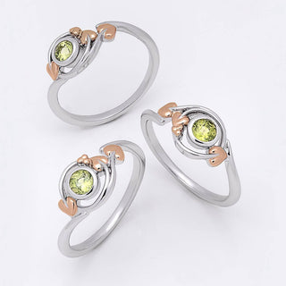 Three silver rings with rose gold accents and round green gemstones, arranged on a clean white background.