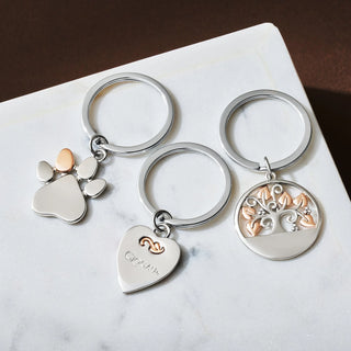 Three silver keychains with different designs on a marble surface