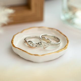 a heart shaped ring with the clogua logo sat in a organic shaped disc