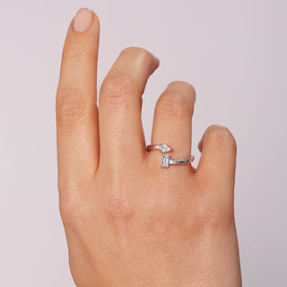 Silver ring on a finger against a light pink background