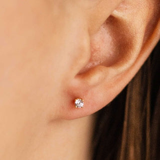 Close-up of an ear wearing a cubic zirconia stud earring with a blurred background