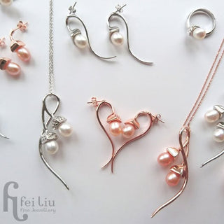 A flat-lay display of fine jewelry from Fei Liu Fine Jewellery, featuring silver and rose gold necklaces, earrings, and a ring, each adorned with small white pearls and rhinestone accents on a clean white background.