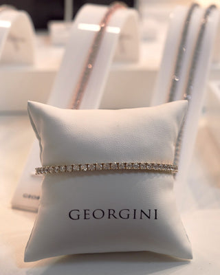 Bracelet on a Georgini branded pillow with blurred jewelry display in the background