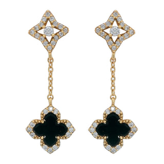A pair of gold dangle earrings featuring a four-petal clover motif with black centers and clear pavé-set stones, suspended from a delicate gold chain with a central round clear stone.