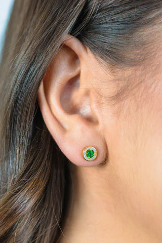 Close-up of an ear wearing a green gemstone with a halo of white czs