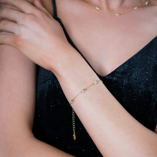 Close-up of a person wearing a delicate pearl bracelet on a black background