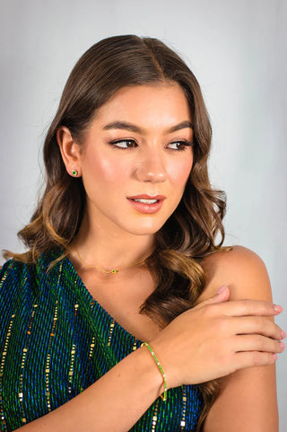 Woman wearing a green beaded top with a plain background