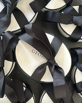 White shoes with black ribbons and 'Georgini' branding on a white background