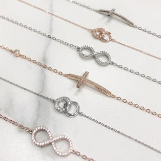 Set of silver and rose gold infinity bracelet on a marble surface