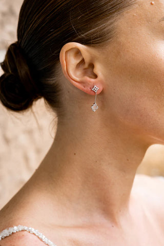 Close-up of a person wearing a silver earring with a small diamond.