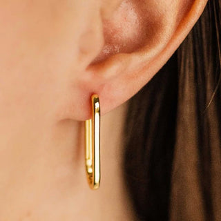Gisser gold hoop earring worn by a person