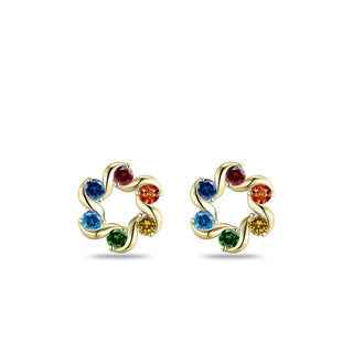 A pair of gold post earrings shaped like a flower with six colorful gemstones in a rainbow sequence, set against a plain white background.