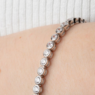 Silver bracelet with clear stones on a wrist against a white background