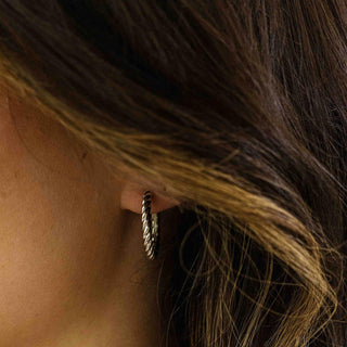 Close-up of an ear wearing a hoop earring with hair partially covering the frame