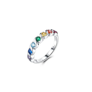 A silver band ring featuring seven small, colorful gemstones in a rainbow sequence, set against a clean white background.