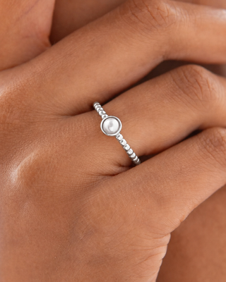 Silver ring with a pearl on a person's finger