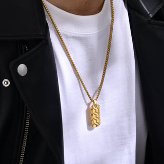 Gold necklace with a pendant on a white shirt and black jacket.