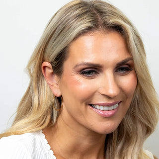 Woman with blonde hair and a white top against a plain background