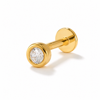 A gold labret piercing stud with a bezel-set clear gemstone, shown on a clean white background with a soft shadow.