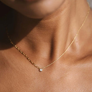 Gold necklace with a small pendant on a person's neck
