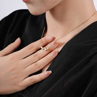 Gold necklace with small Czs worn by a person against a neutral background