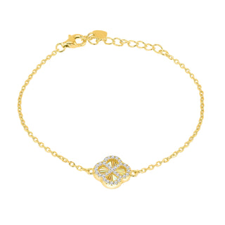 A delicate yellow gold chain bracelet with a central clover-shaped charm. The charm features a textured gold center surrounded by a halo of small clear stones, set against a clean gray gradient background.