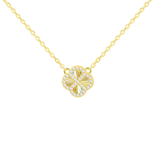 A gold chain necklace with a clover-shaped pendant featuring a gold center and a border of small clear stones, shown against a light gray gradient background.
