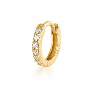 A yellow gold huggie hoop ring featuring a row of round-cut clear gemstones on the front, photographed on a clean white background with a soft reflection.