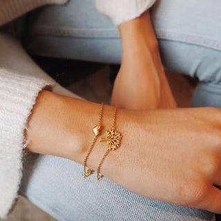 Gold bracelet with a tree design on a wrist against a blurred background