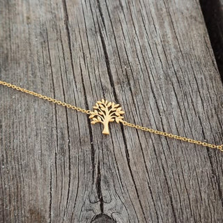 Gold tree-shaped pendant on a chain against a wooden background