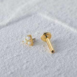 Gold earring on a textured white surface