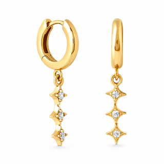 A pair of gold huggie hoop earrings with dangling starburst charms set with small clear stones, shown on a plain white background.