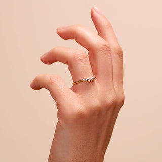 Hand wearing a gold ring with small diamonds on a beige background