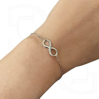 Silver bracelet with an infinity symbol on a wrist against a white background