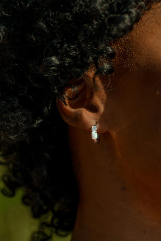 Close-up of an ear with a silver earring against a blurred background