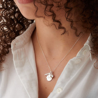 women wearing a necklace with a letter a pendant, a round disc and a pink crystal