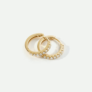 Pair of gold hoop earrings with small diamonds on a light gray background