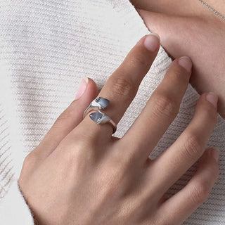 Close-up of a hand wearing two silver rings on a textured white background