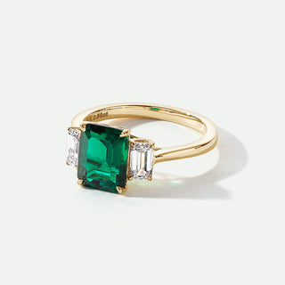 Gold ring with a green gemstone on a white background