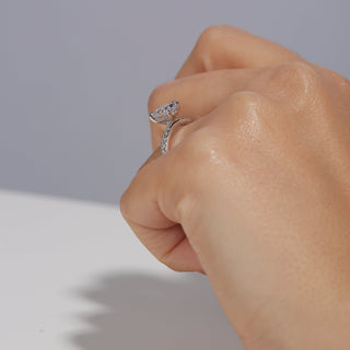 Hand wearing a silver ring with a diamond on a neutral background