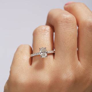 Diamond ring on a finger against a neutral background