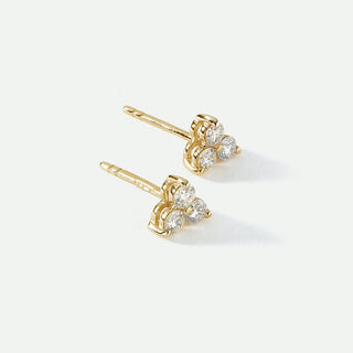 Gold earrings with  a trio clear gemstones on a white background