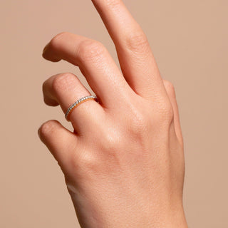 Hand wearing a diamond ring on a beige background