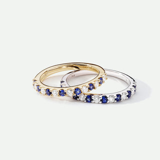 Two gold and silver rings with blue and clear gemstones on a white background