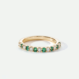 Gold ring with green and white gemstones on a white background