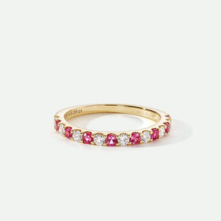 Gold ring with pink and white gemstones on a white background