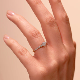 Close-up of a hand wearing a diamond ring on a beige background