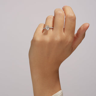 Hand wearing a diamond ring on a plain background