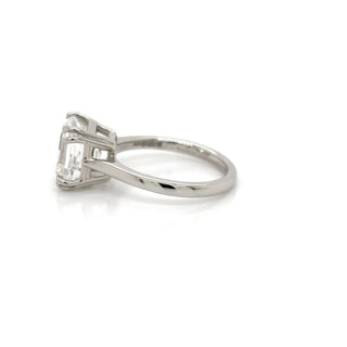 Diamond ring with emerald-cut center stone on a white background